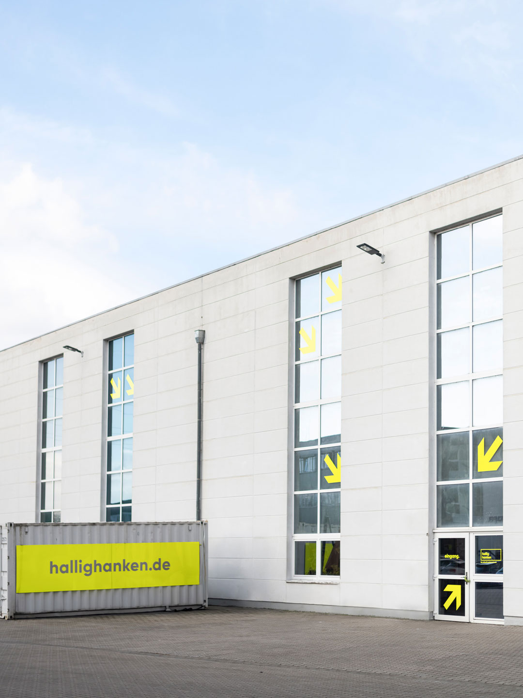 Leitsystem von Hallig Hanken: Außenbeschriftung des Gebäudes mit gelben Pfeilen und Container