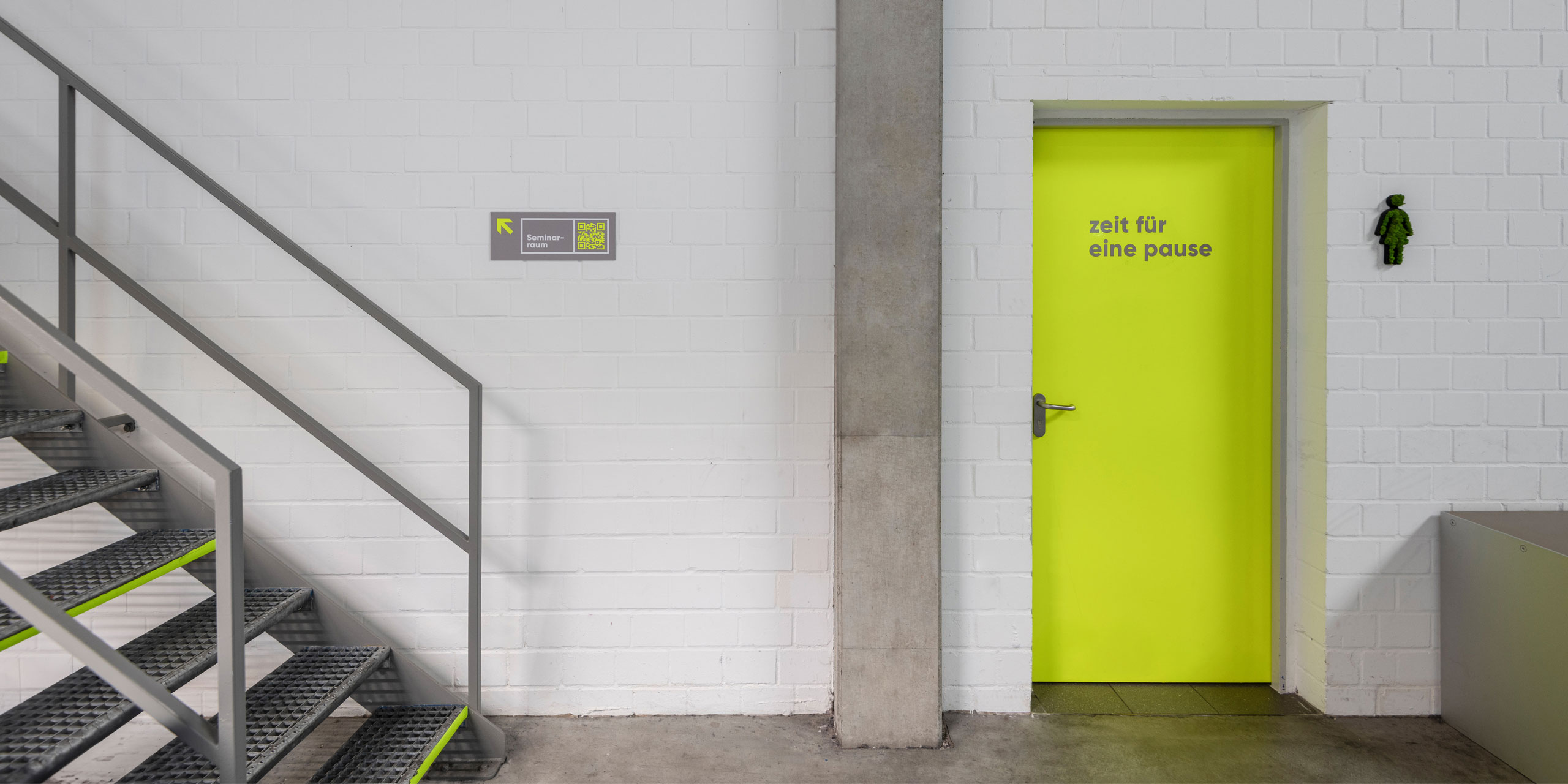 Leitsystem von Hallig Hanken im Innenbereich: gelbe Tür mit Beschriftung „Zeit für eine Pause“ und Hinweisschild zum Seminarraum
