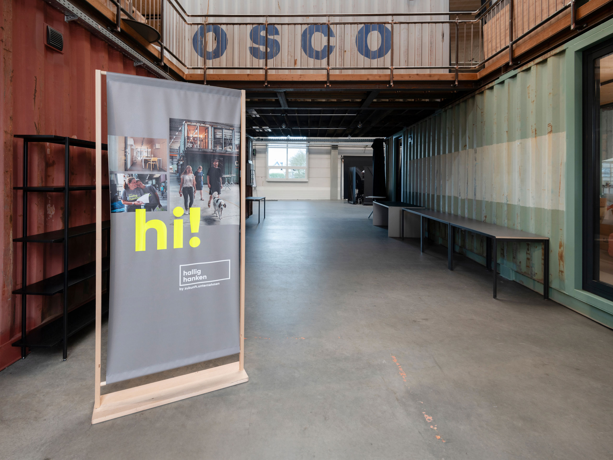 Roll-up von Hallig Hanken mit dem Schriftzug „hi!“ im Eingangsbereich – Markenauftritt im Raum