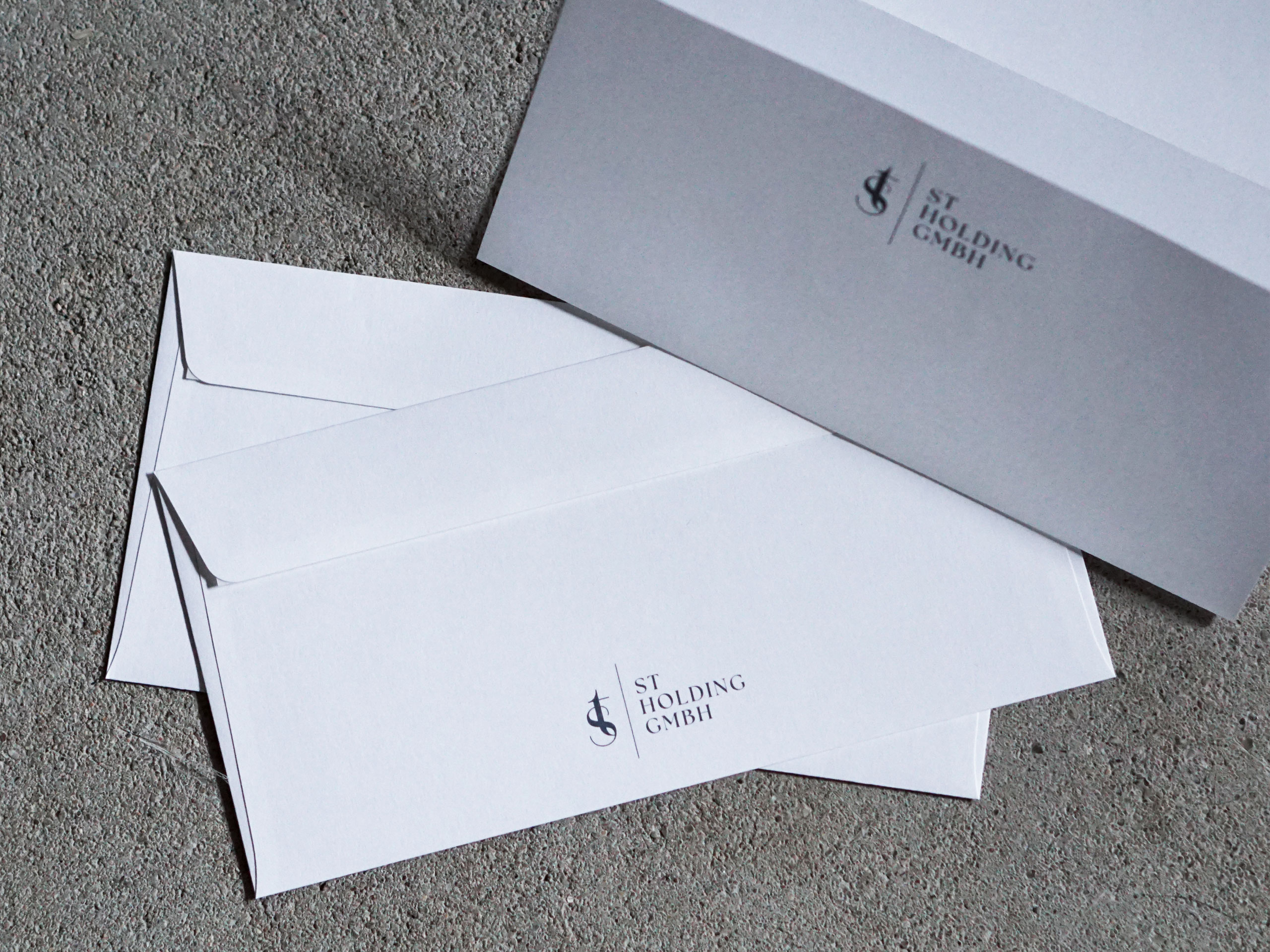 Weiße Briefumschläge mit Logo der ST Holding GmbH auf der Vorderseite
