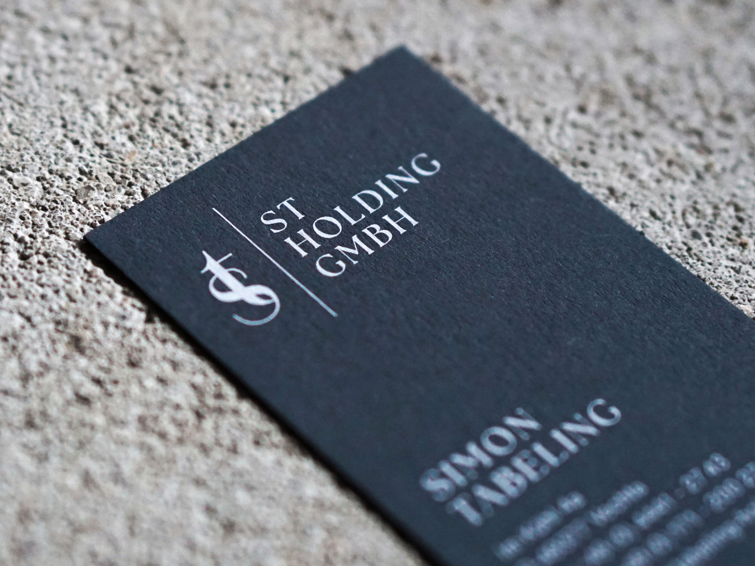 Nahaufnahme einer ST Holding GmbH Visitenkarte aus hochwertigem, strukturiertem Papier mit weißem Druck