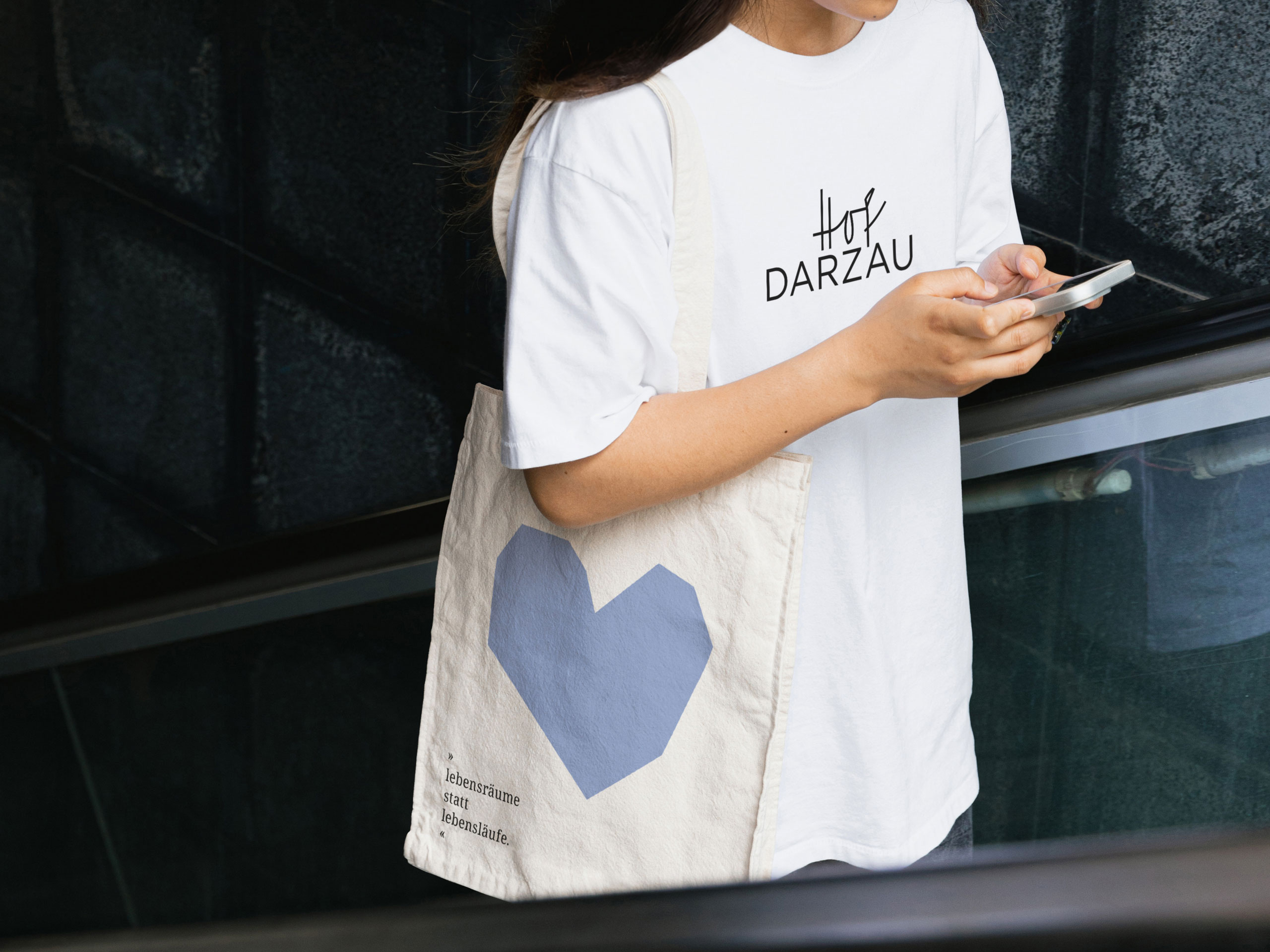 Frau trägt T-Shirt mit Hof-Darzau-Logo und Stoffbeutel mit Herzmotiv – Branding und Corporate Design Umsetzung des Projekts "Hof Darzau"